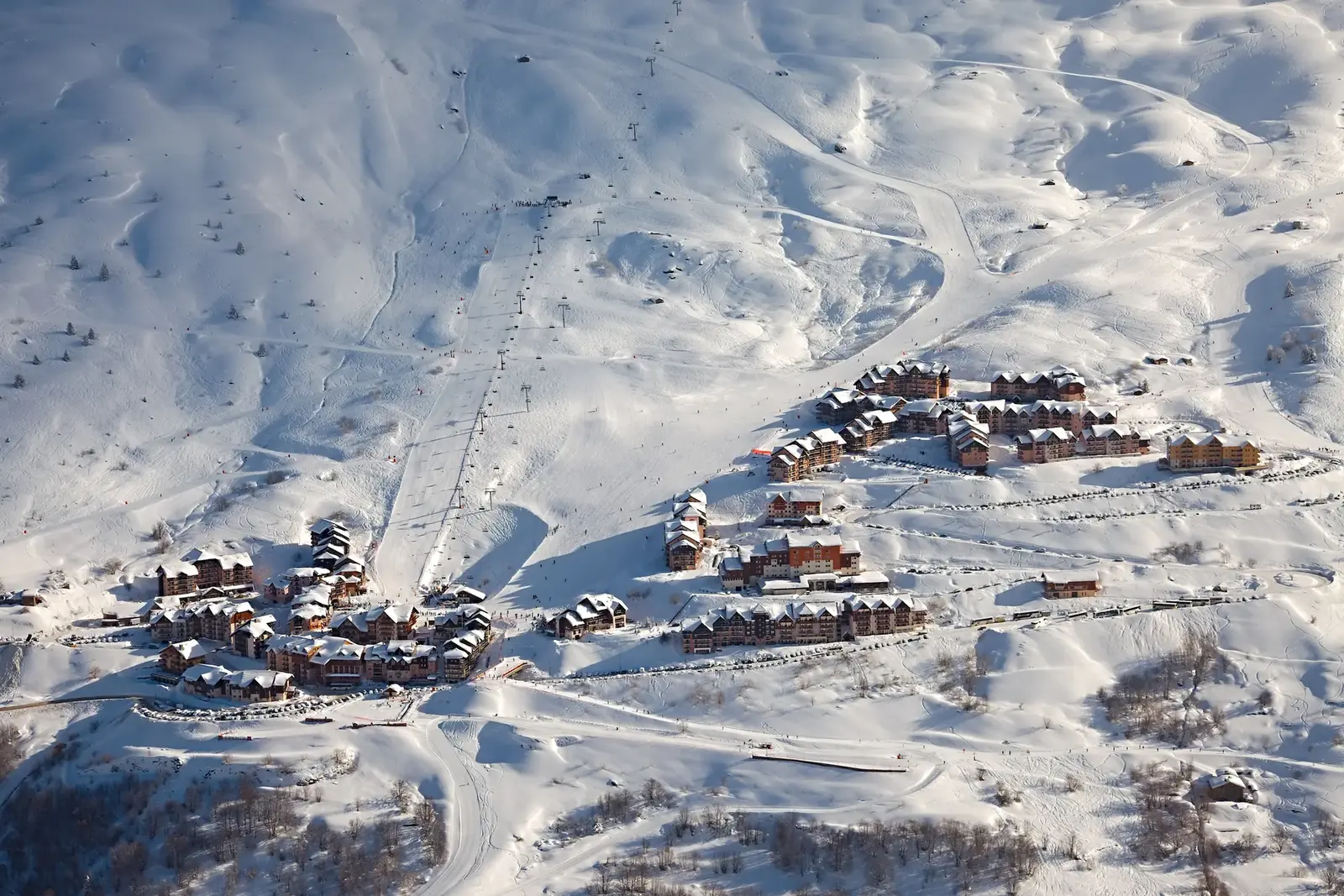 Les chalets de Valmeinier sous la neige vus d'en haut, au milieu des pistes du domaine Galibier-Thabor en Maurienne